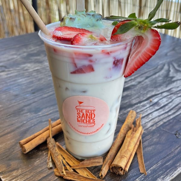 A strawberry and cream drink with mint ice cream, garnished with a strawberry and cinnamon sticks.
